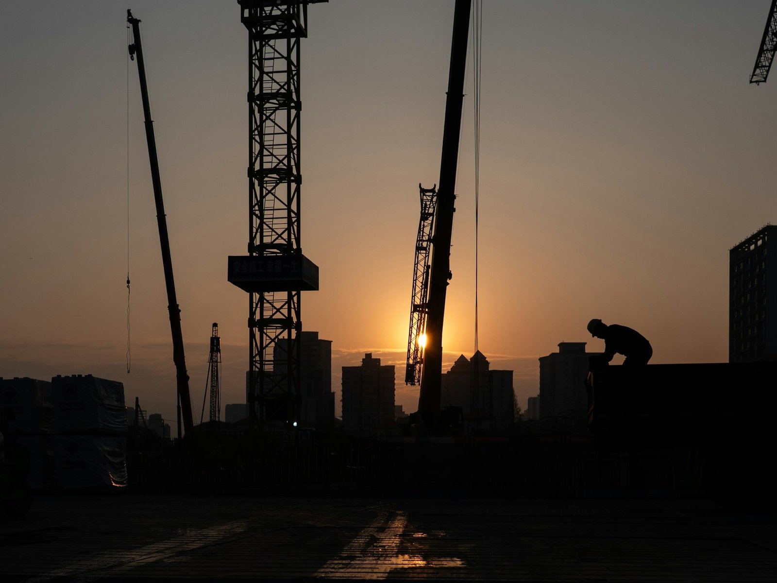 Construction workers silhouetted at sunset